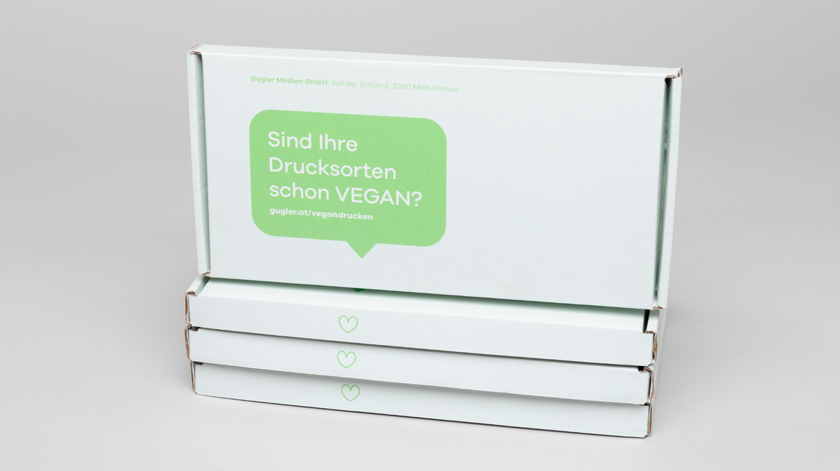 Ein Stapel print Mailing Boxen zum Thema VEGAN drucken mit Sprechblase "Sind Ihre Drucksorten schon VEGAN?"