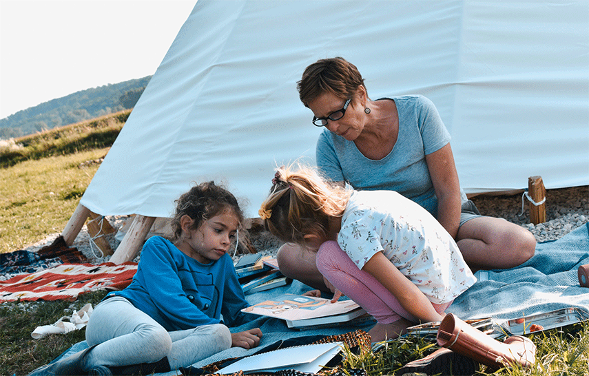 Eine Frau und 2 Kindern schauen sich Bilderbücher an 